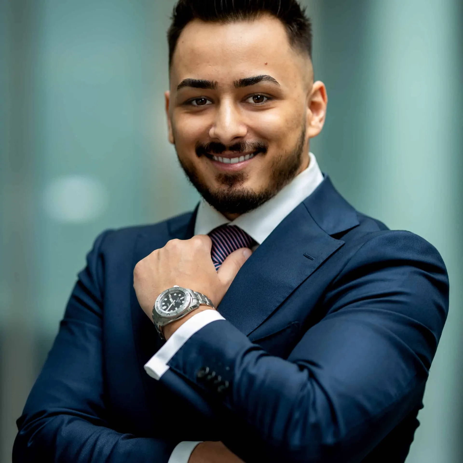 Business Portrait: Mann im dunkelblauen Anzug vor moderner Glasfassade
